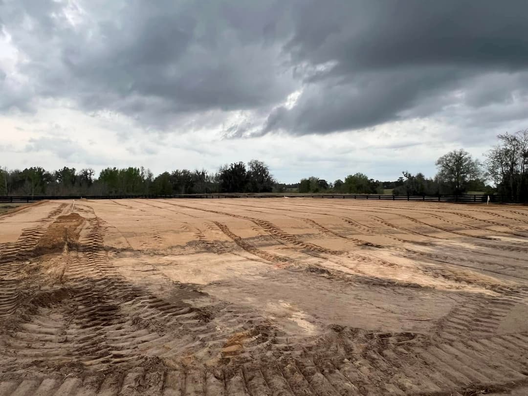 An expansive, plowed dirt field under a cloudy sky, ideal for agriculture or landscaping.
